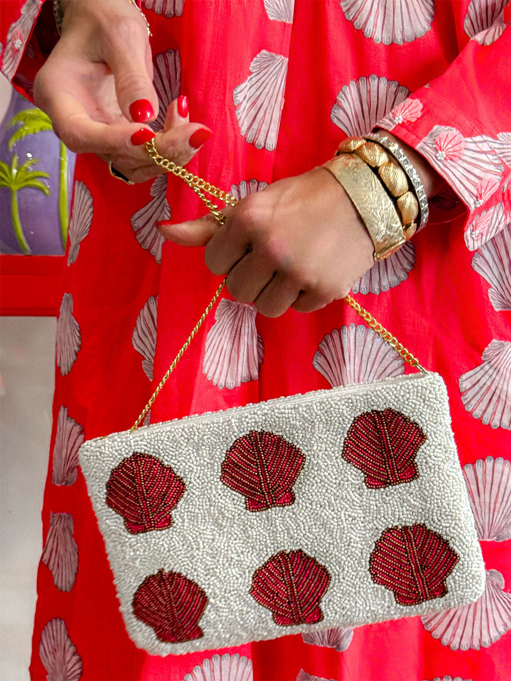 Nimo With Love beaded bag worn as shoulder bag — white base with coral shell motifs and delicate gold chain