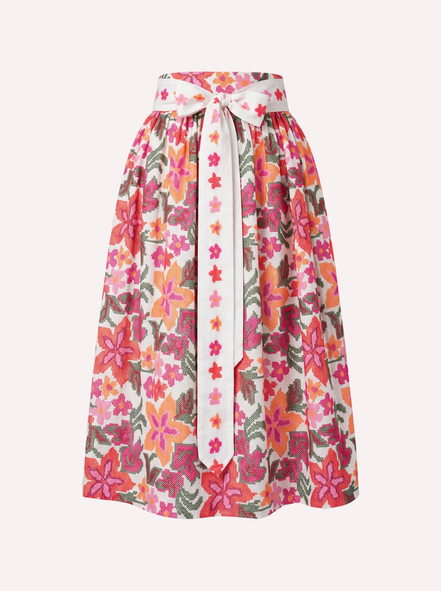 White Nimo x Münchner Manufaktur cotton dirndl apron featuring an all-over vibrant pink, orange, and green floral cross-stitch pattern.