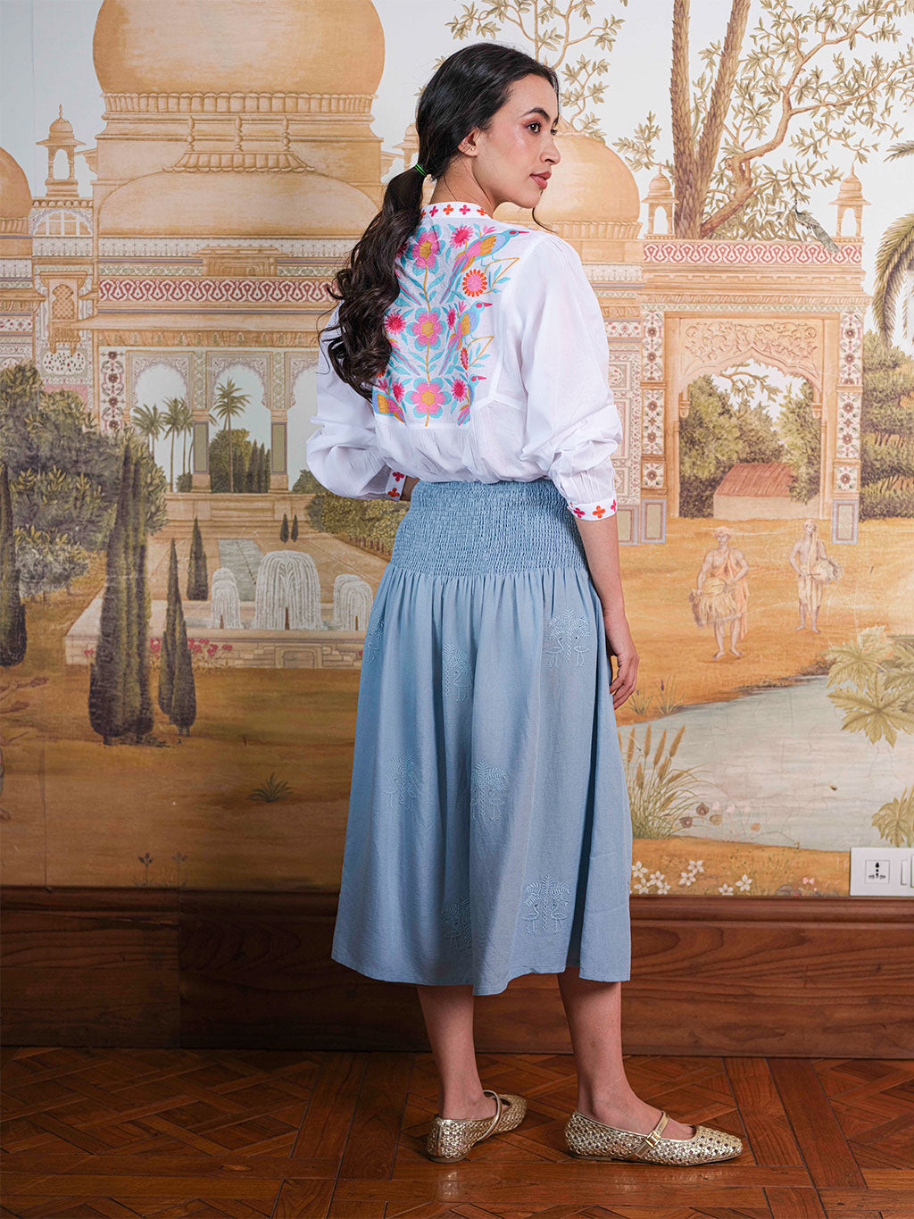 High-resolution detail of the intricate, multi-colored bird and floral motif on the back of the Catnep resort blouse.