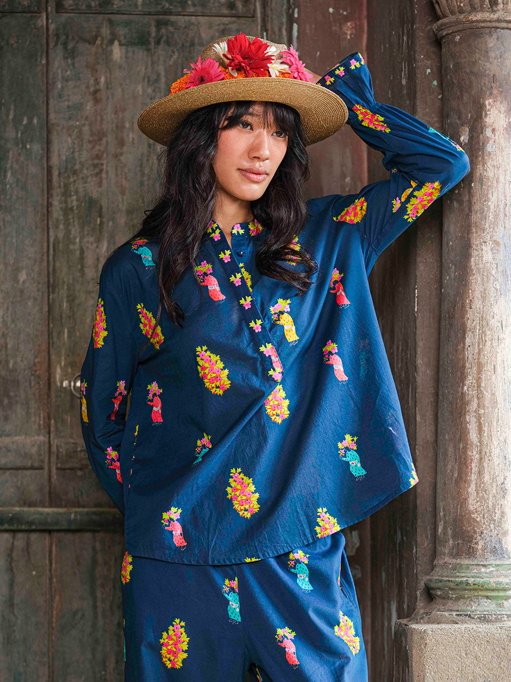 Woman wearaning a navy blue bohemian tunic blouse with a colorful print and and long, puffed sleeves.