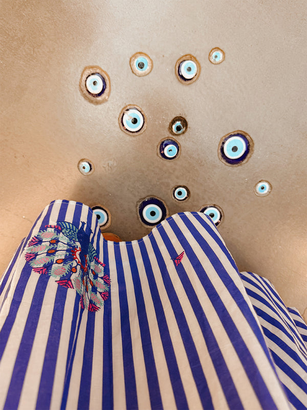 Detailed view of the artisanal peacock embroidery on striped cotton fabric