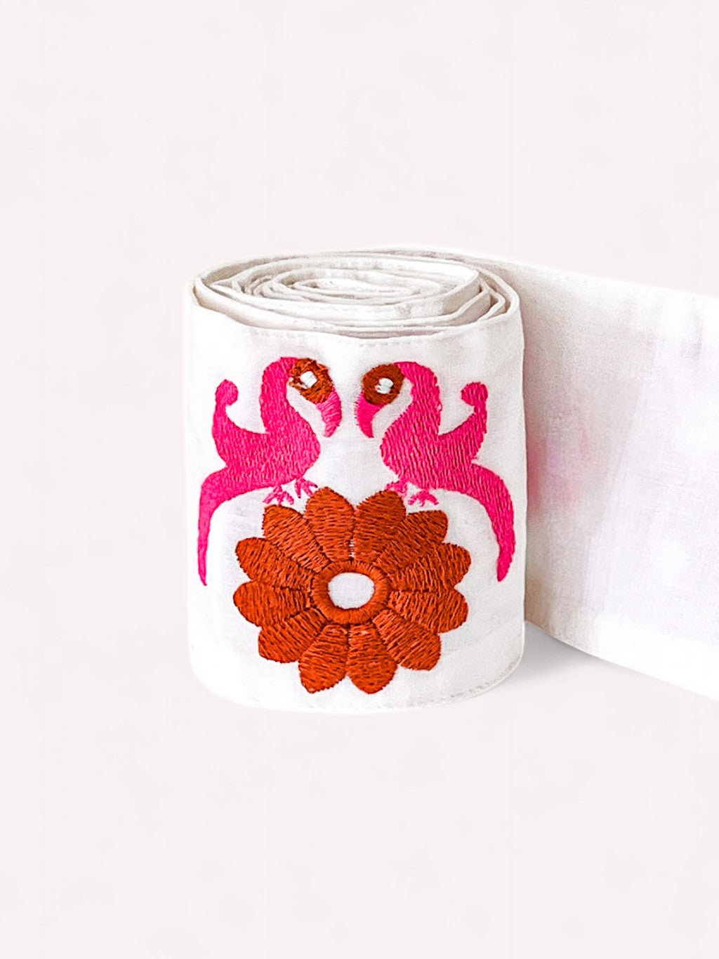Close-up of the rolled Belt Gujarat Birds in white organic cotton showcasing the vibrant pink and orange bird embroidery.