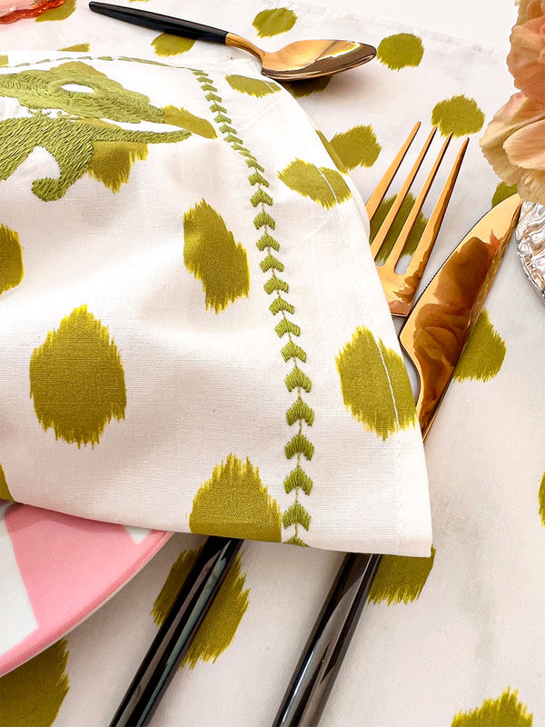 Close-up of tactile hand-embroidery and green ikat dot print
