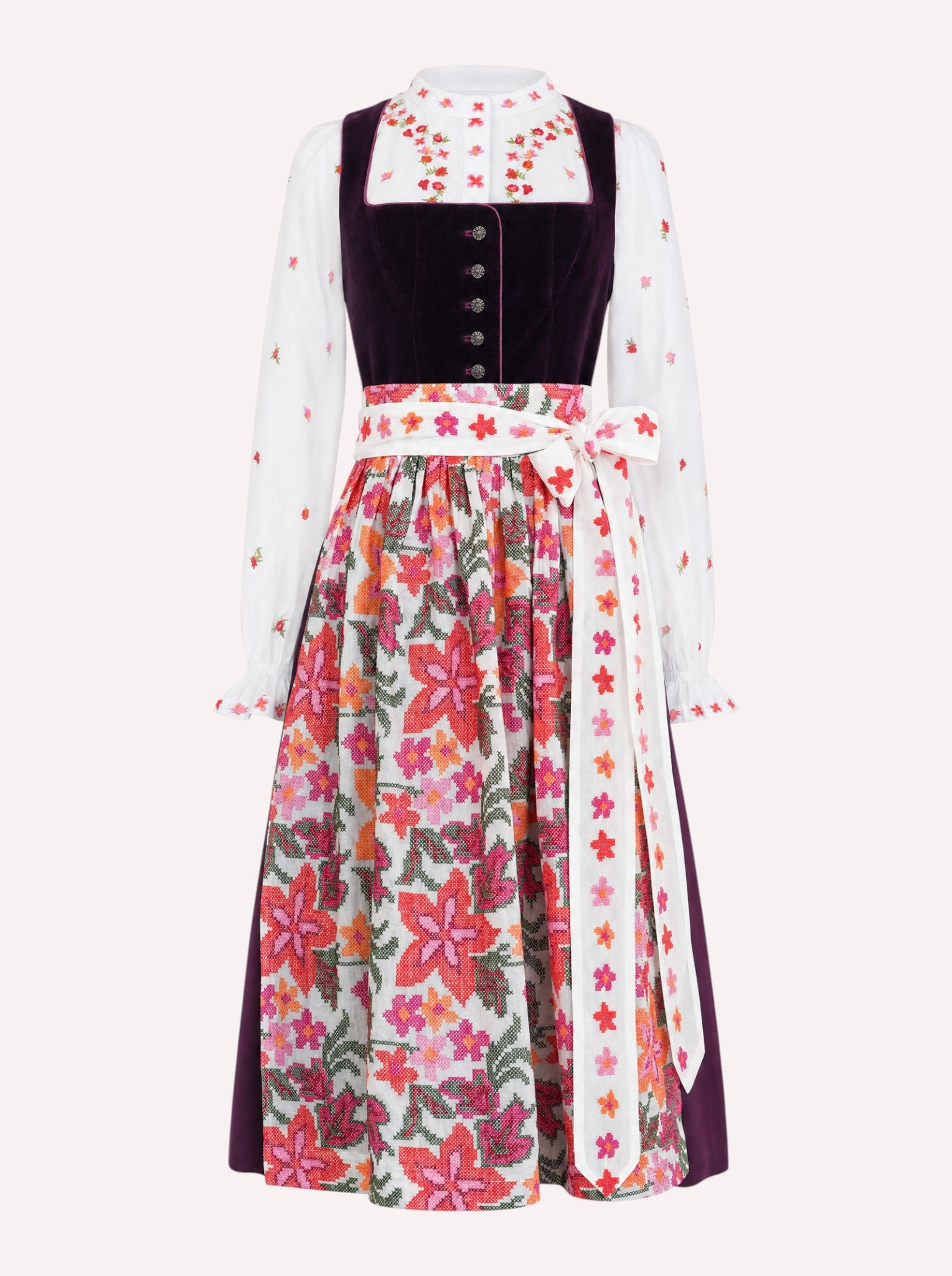 A traditional German dirndl dress featuring a white Nimo dirndl blouse with colorful floral embroidery on the sleeves and the Nimo dirndl apron with a vibrant multicolor floral cross stitch pattern.