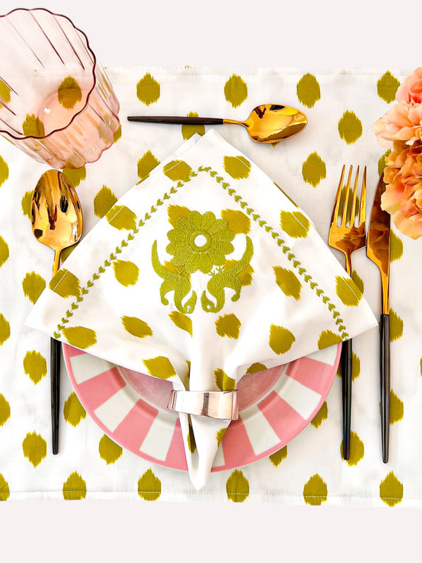 Elegant table setting with green ikat napkins and gold cutlery