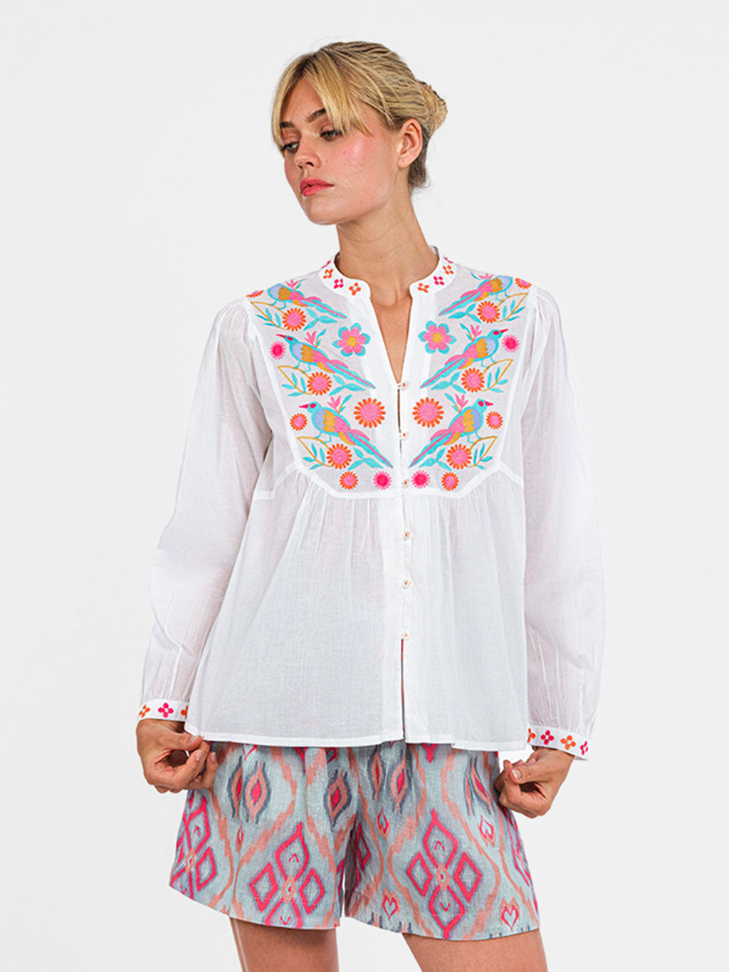 White organic cotton Catnep blouse by Nimo With Love featuring vibrant bird and floral embroidery on the front yoke.