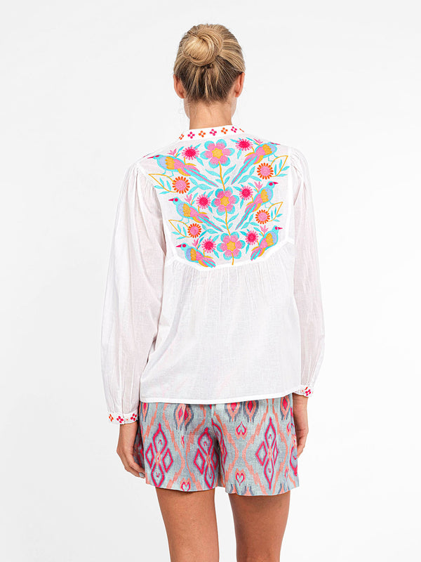 High-resolution detail of the intricate, multi-colored bird and floral motif on the back of the Catnep resort blouse.