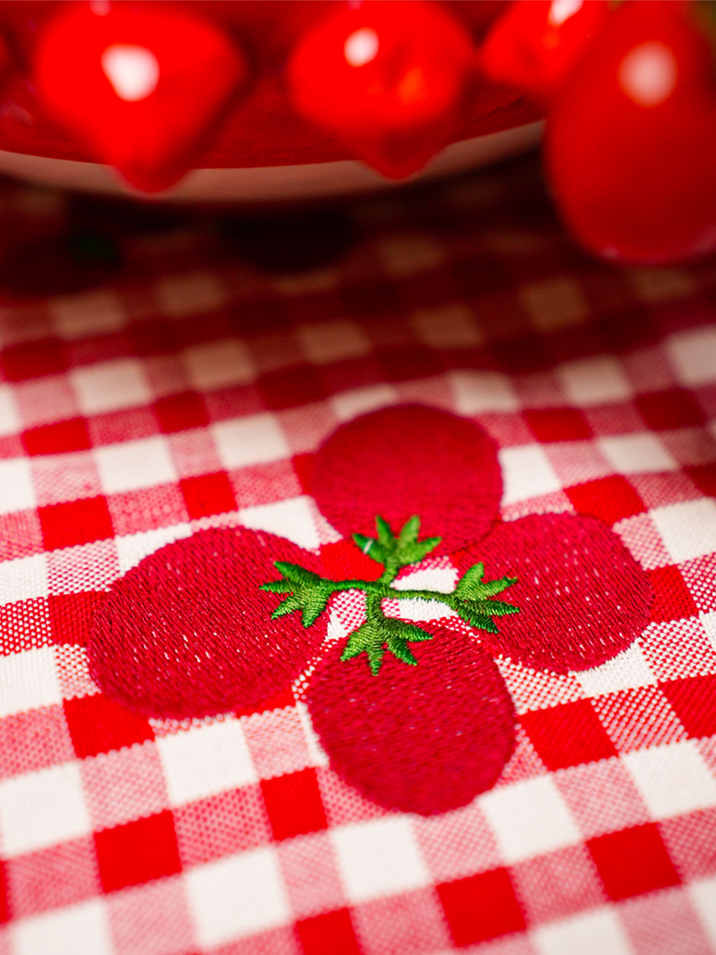Sophisticated red gingham linen with detailed mediterranean motif embroidery for a charming home aesthetic.