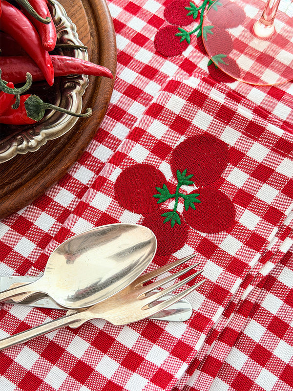Charming red and white gingham napkins with vegetable motifs, perfect for a curated summer table setting.